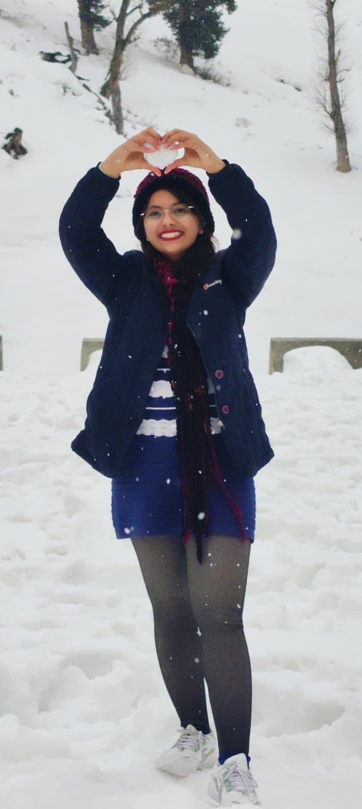 Riya making a heart shape with her hands in the snow